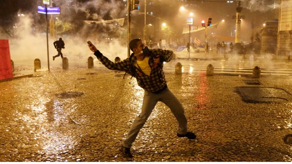 A protesters throws a missile amid clouds of smoke in the capital