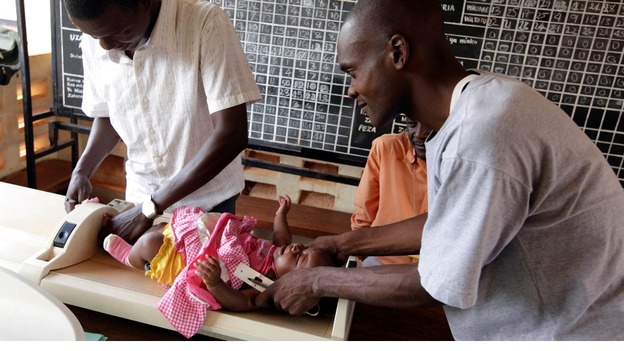 Kenyan nurses weigh a child before she is given an injection as part of a malaria vaccine trial in Kenya