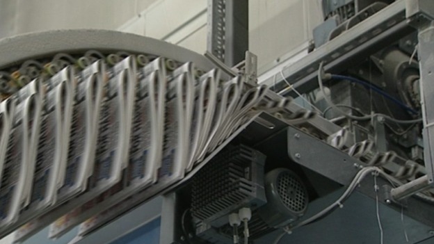 Newspapers being printed in a factory.