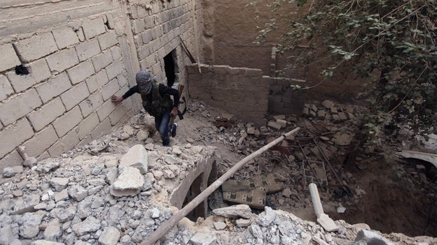 A Free Syrian Army fighter carries his weapon as he walks on the rubble of a damaged building in Deir al-Zor.