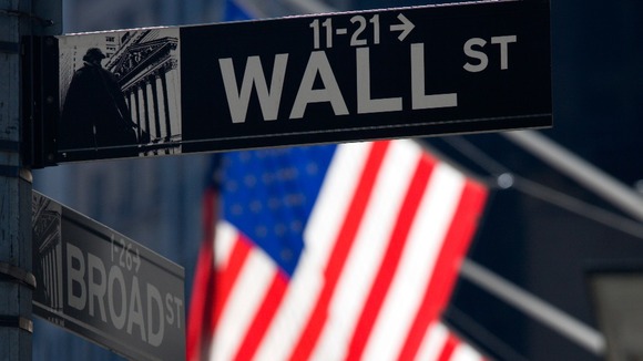 The sign for Wall Street with Stars and Stripes behind.