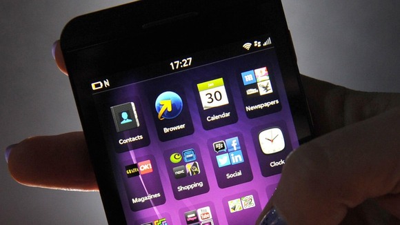 A person holding a BlackBerry touchscreen device.