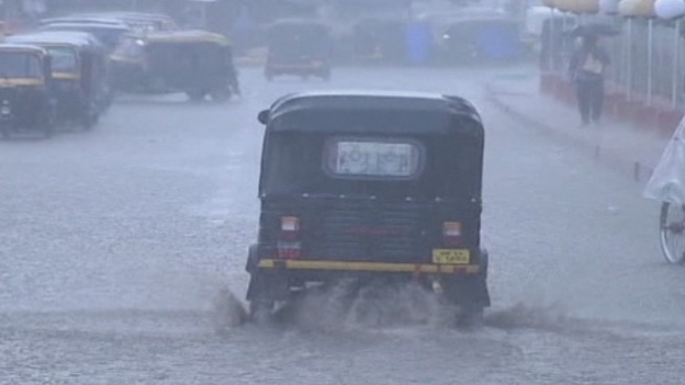 An auto rickshaw drives through a flooded street in eastern India