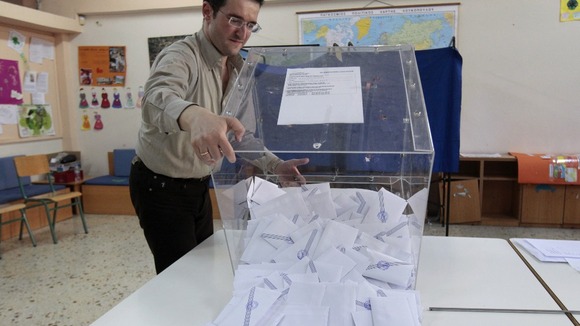 A judicial representative empties a ballot box after the end of voting at a polling station in Athens.