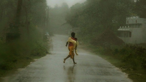 A girl runs for shelter in heavy rain brought by Cyclone Phailin in Ichapuram town in Srikakulam district.