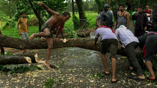 Men try to remove fallen trees from a road in the Indian state of Odisha.