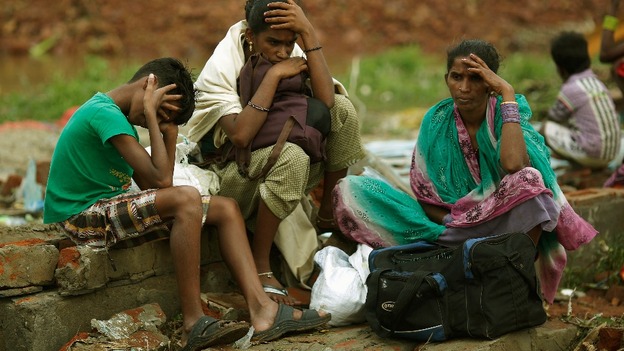 A family waits to board a boat as they return to their villages after Cyclone Phailin hit.