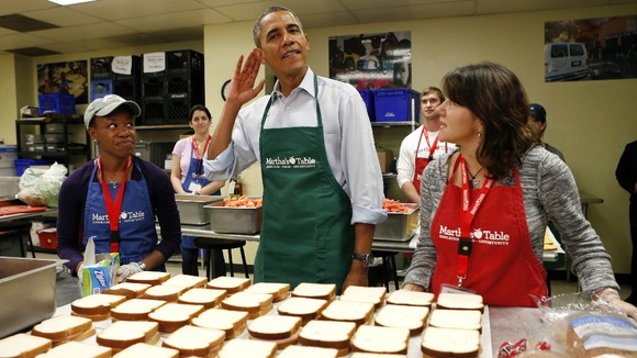 President Barack Obama tries to hear a question from a reporter as he helps the volunteers.