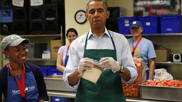 President Barack Obama has trouble closing a plastic bag at Martha's Table, a kitchen that provides meals for the homeless.