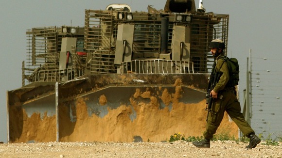 An Israeli soldier walks past military bulldozers near Kibbutz Kissufim, just outside Gaza