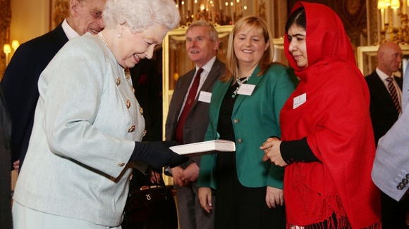 Malala presents the Queen with a copy of her book.