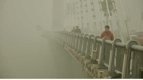 People walk on a bridge during a smoggy day in Jilin, Jilin province