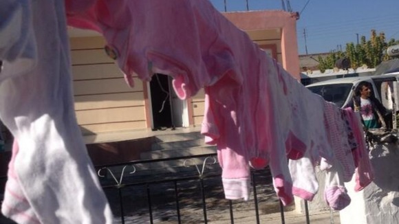 Children's clothes hang on the washing line outside the home.