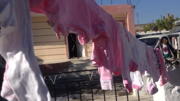 Children's clothes hang on the washing line outside the home.