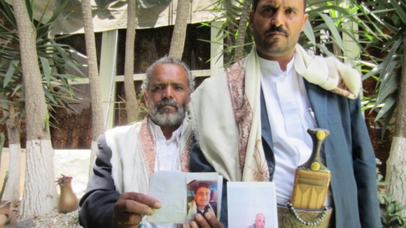 Hussain Jamil al-Qawli holds a picture of his 20-year-old son killed, and Muhammad al-Qawli holds a picture of his brother Ali.