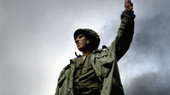 An Iraqi fighter strikes a defiant pose on top of a captured US tank.