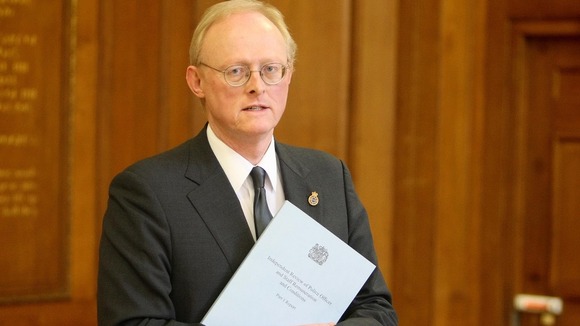 Tom Winsor with a copy of his review into police pay and conditions
