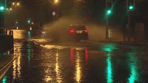 Cars drive through a flooded road in Plymouth.