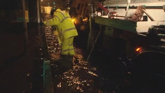 Highway maintenance men try to clear drains in Plymouth to stop the flooding.