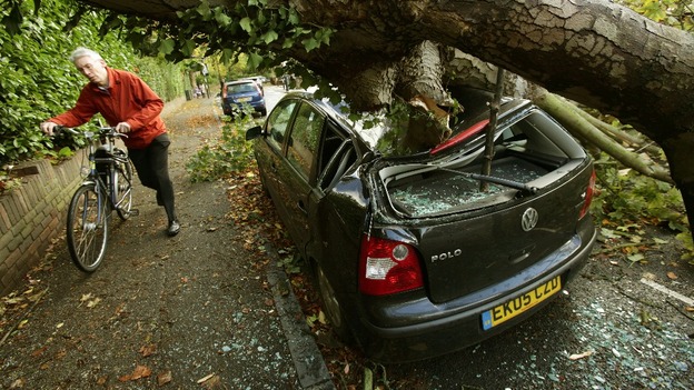A cyclist carefully passes a crushed car in Hornsey.