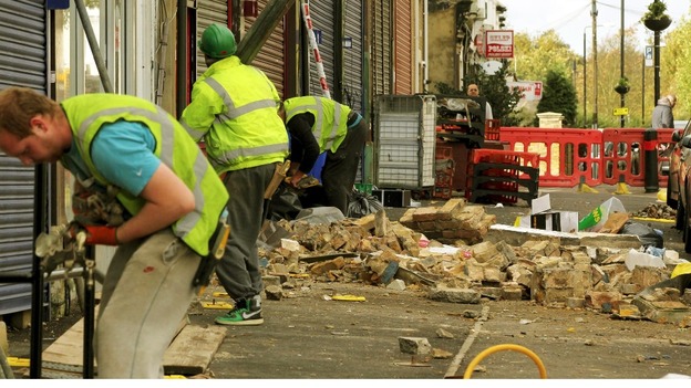Workers clean up damaged brick work in Leyton, east London