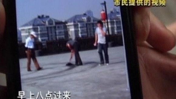 Residents of Nanjing in Jiangsu Province clear the Ferrari tyre marks