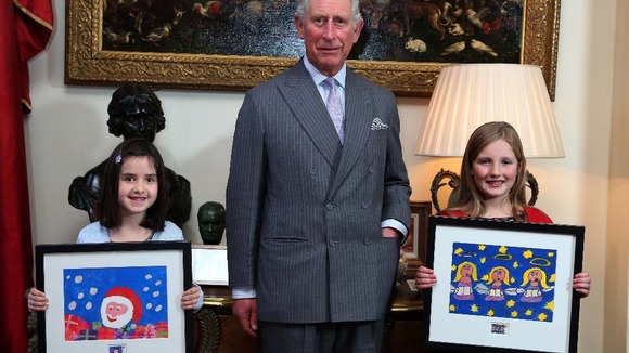 Prince Charles presents Molly Robson (left), aged seven, and Rosie Hargreaves, aged 10, with framed copies of their designs.
