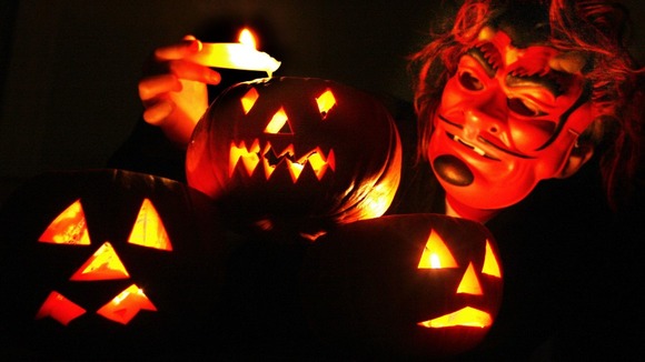 A child gets ready for Halloween by lighting up lanterns dressed as a devil.