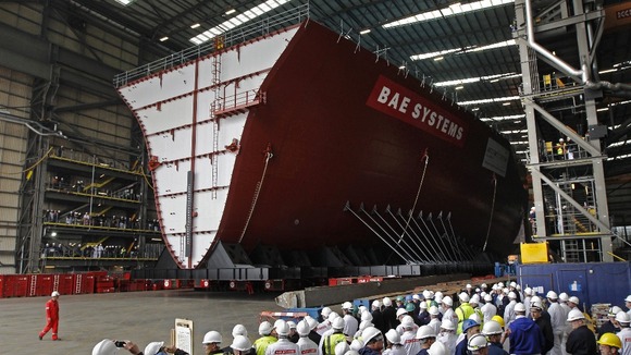 Workers watch as the forward section of aircraft carrier HMS Queen Elizabeth as it is moved on to barge on Portsmouth in May 2012.
