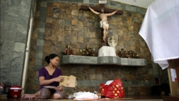 A woman puts a child to sleep behind the altar