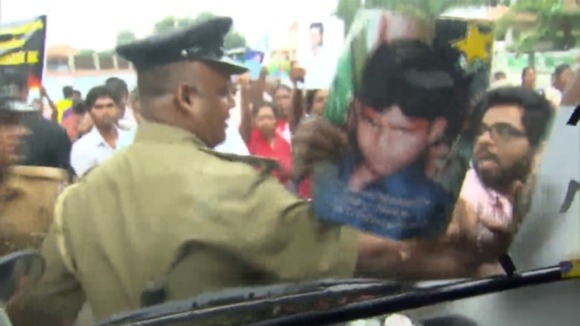 Police try to stop protesters as they thrust images of their disappeared loved ones at a reporter van.