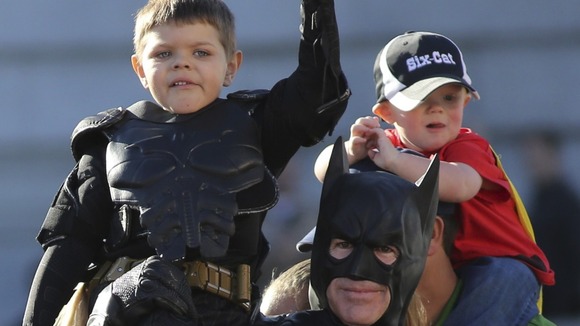 Miles waves to the crowd on the shoulders of Batman.