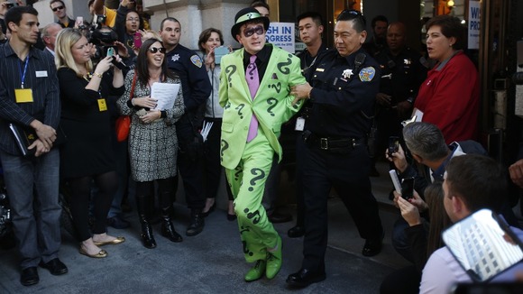 The Riddler is taken away by a San Francisco Police officer after being apprehended by the five-year-old.