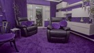 The living room boast purple walls, carpets and cushions.