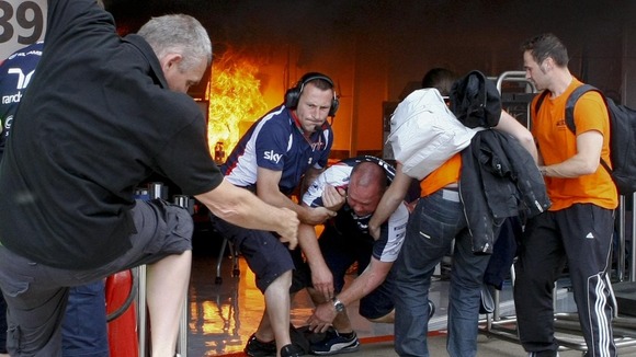 Team members are dragged from the Williams garage after a blaze broke out