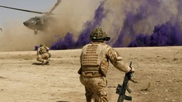 British soldiers cover themselves from dust as a helicopter lands in Helmand