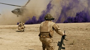British soldiers cover themselves from dust as a helicopter lands in Helmand