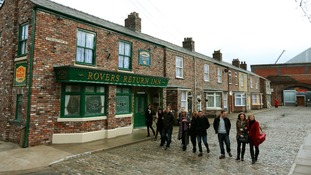 Cast members from Coronation Street walk along the cobbles of the new set.