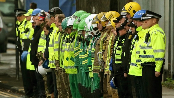 Emergency Services personnel form a Guard of Honour salute as an ambulance carries one of the victims away
