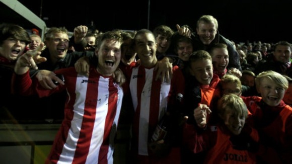 Brackley's players celebrate with fans after beating Gillingham.