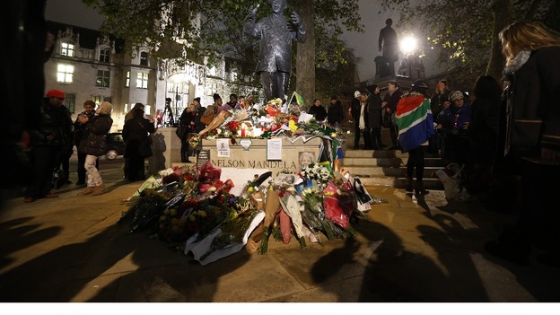 People gather around a statue of Nelson Mandela at Parliament Square.