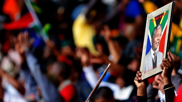 A woman holds a portrait of Nelson Mandela at the First National Bank (FNB) Stadium