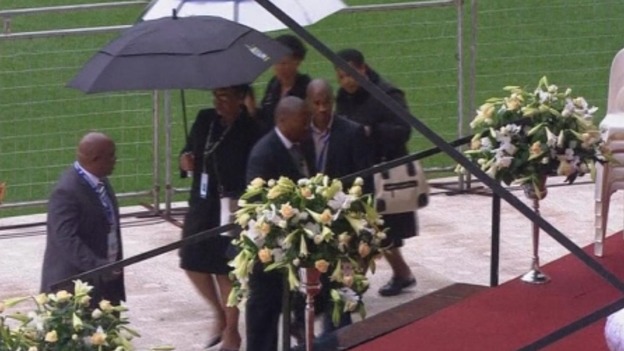 Winnie Mandela can be seen carrying the black umbrella