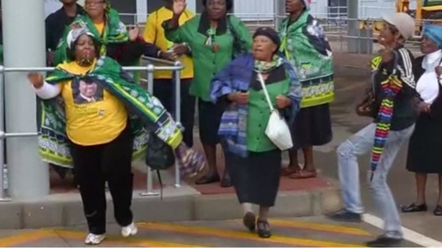 Women dance as they wait for a bus