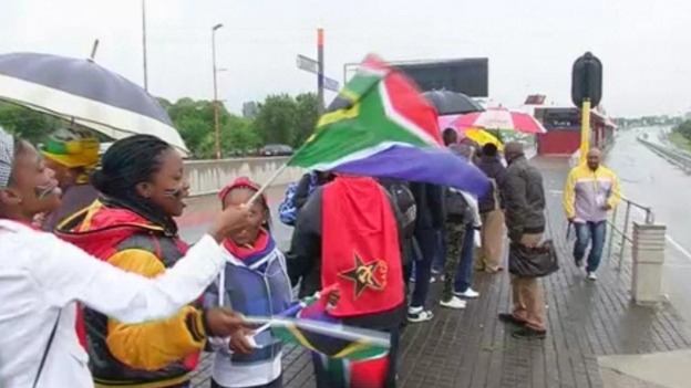 People wave South African flags in the queue