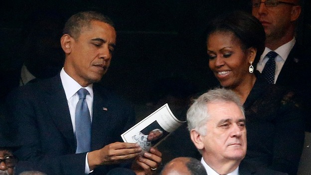President Obama looks through a programme with his wife Michelle