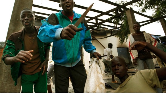 A young boy involved in the looting of a mosque brandishes his knife in front of the cameras.