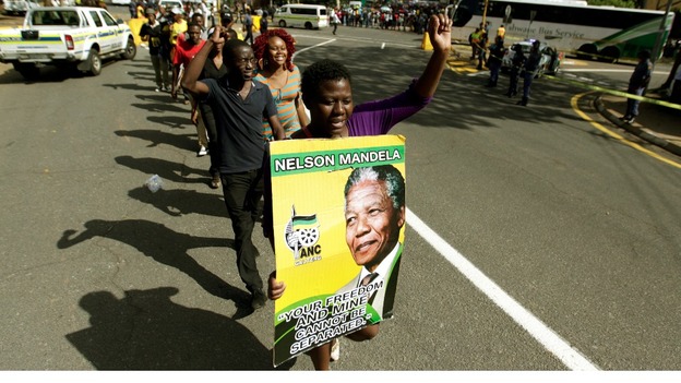 A woman carries a poster of former South African President Nelson Mandela as she queues to view his body.