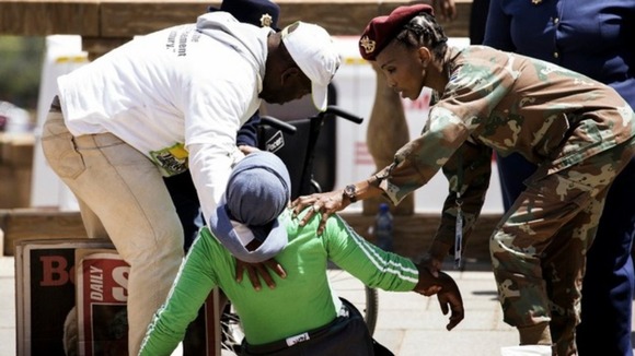 Soldiers help a woman as she collapses after seeing Nelson Mandela's coffin.