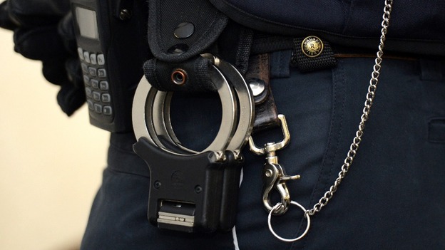 A judicial officer carries handcuffs on his belt.